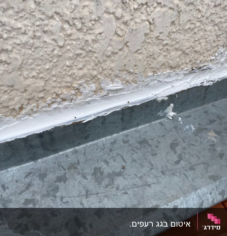 חומר איטום לבן על גג מתכת אפור